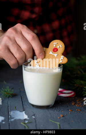 Gingerbread cookie e il latte. Uomo con gingerbread man cookie e andando a sprofondare in un bicchiere di latte. Natale arte cibo Foto Stock