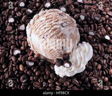 Un convogliatore di cappuccino gelato con scaglie di cioccolato e panna montata su un letto di chicchi di caffè Foto Stock
