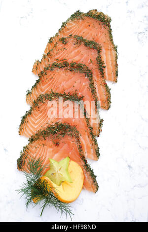 Scavata (salmone gravlax) con aneto, guarnita con persimmon e starfruit Foto Stock