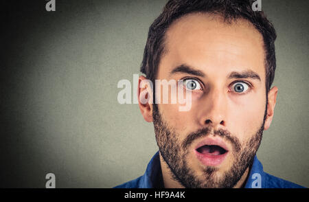 Stupito l'uomo. Closeup ritratto ragazzo cerca sorpreso in piena incredulità isolato sul muro grigio Sfondo. Emozioni umane espressione facciale Foto Stock