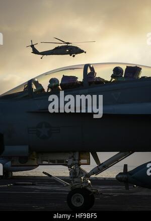 Un Boeing F/A-18E Super Hornet fighter aircraft taxi sul ponte di volo dell'USN Nimitz-class portaerei USS Nimitz al tramonto Dicembre 5, 2016 nell'Oceano Pacifico. Foto Stock