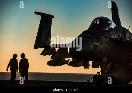 I marinai DEGLI STATI UNITI condotta pre-controlli di volo su un Boeing F/A-18E Super Hornet degli aerei da caccia al tramonto sul ponte di volo dell'USN Nimitz-class portaerei USS Dwight D. Eisenhower Dicembre 11, 2016 nel mar Mediterraneo. Foto Stock