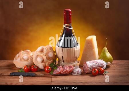 Il vino rosso, pane, formaggio e salame sul tavolo di legno Foto Stock