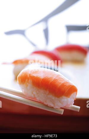 Bacchette tenendo il nigiri sushi e salmone Foto Stock