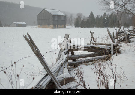 Una banca di ontario fienile con split cedar cancellata nella neve in inverno Foto Stock