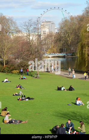 Turisti che si godono una soleggiata giornata di marzo in St James Park con delle Guardie a Cavallo e il London Eye al di là Foto Stock