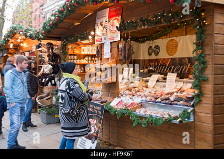 Shoppers persone che fanno shopping alle cabine del mercato di Natale a St Nicholas Fayre in inverno York North Yorkshire Inghilterra Regno Unito GB Gran Bretagna Foto Stock