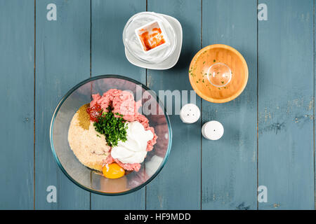 Gli ingredienti alimentari per preparare le polpette di carne sul tavolo da cucina Foto Stock