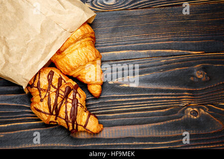 Due cornetti freschi su sfondo di legno Foto Stock