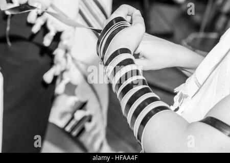 Bar Mitzvà cerimonia un giovane ragazzo di 13 recante Tefillin. Close up di mani e braccia Foto Stock