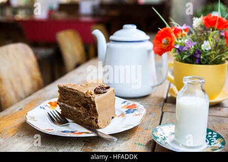 Torta al caffè, una pentola di tè e latte su un tavolo in un ambiente caffè. Foto Stock
