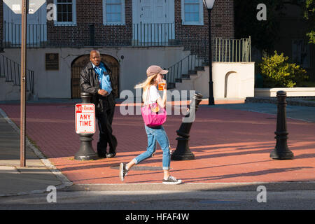 Stati Uniti d'America Sud Carolina Charleston street scene ragazza bionda passeggiate passato nero americano africano appoggiata contro bollard nessun segno di parcheggio Foto Stock