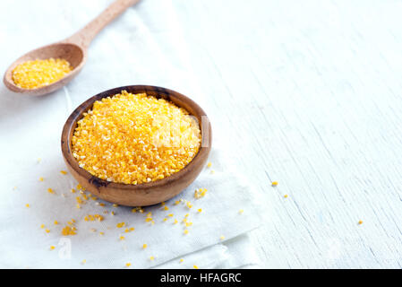 Materie organici di polenta di farina di mais (grits) in ciotola di legno su sfondo bianco con spazio copia - il cibo sano ingrediente Foto Stock