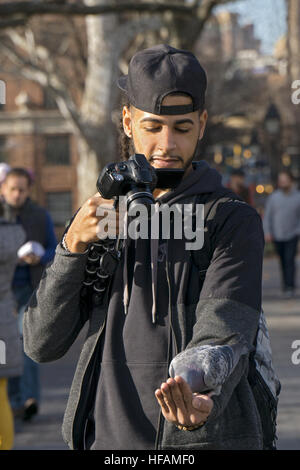 Foto di un uomo prendendo un selfie di se stesso mentre si alimenta un piccione in Washington Square Park nel Greenwich Village di New York City Foto Stock