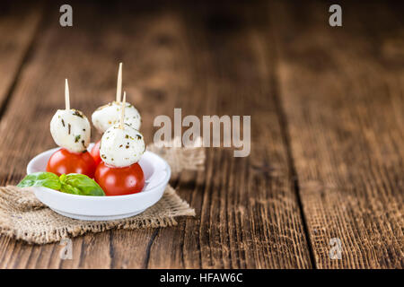 Le sfere di mozzarella con pomodori (messa a fuoco selettiva) su sfondo di legno Foto Stock