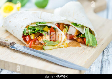 Wrap di pollo (dettagliate di close-up shot; messa a fuoco selettiva) su sfondo di legno Foto Stock