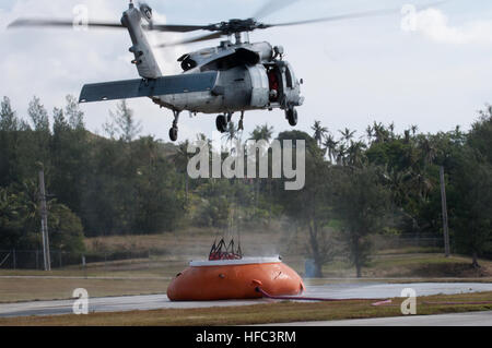 SANTA RITA, Guam (feb. 20, 2015) - Un MH-60S Knighthawk con "l'isola Cavalieri" di elicottero di mare squadrone di combattimento (HSC)-25, posiziona il puntatore del mouse su un'acqua di "Pumpkin' per raccogliere acqua da un "Bambi Bucket" per condurre una "Bambi Bucket antincendio aerea " missione di addestramento, come parte dei fuochi di estinzione missioni di formazione effettuata il 20 febbraio presso la Naval Magazine, munizioni navali comando, Base Navale Guam (BNG). (U.S. Navy Foto di Jeff Landis/RILASCIATO) HSC-25 conduce wildfire 150220 formazione-N-OG363-004 Foto Stock