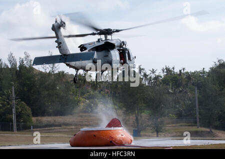 SANTA RITA, Guam (feb. 20, 2015) - Un MH-60S Knighthawk con "l'isola Cavalieri" di elicottero di mare squadrone di combattimento (HSC)-25, posiziona il puntatore del mouse su un'acqua di "Pumpkin' per raccogliere acqua da un "Bambi Bucket" per condurre una "Bambi Bucket antincendio aerea " missione di addestramento, come parte dei fuochi di estinzione missioni di formazione effettuata il 20 febbraio presso la Naval Magazine, munizioni navali comando, Base Navale Guam (BNG). (U.S. Navy Foto di Jeff Landis/RILASCIATO) HSC-25 conduce wildfire 150220 formazione-N-OG363-006 Foto Stock