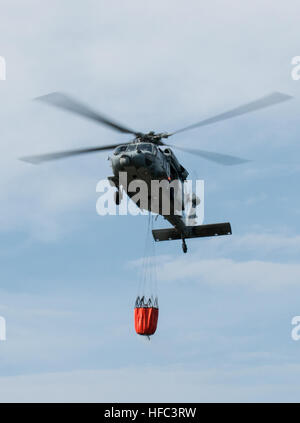 SANTA RITA, Guam (feb. 20, 2015) - Un MH-60S Knighthawk con "l'isola Cavalieri" di elicottero di mare squadrone di combattimento (HSC)-25, porta un "Bambi Bucket" di acqua per l'estinzione di una missione di addestramento, come parte dei fuochi di estinzione missioni di formazione effettuata il 20 febbraio presso la Naval Magazine, munizioni navali comando, Base Navale Guam (BNG). (U.S. Navy Foto di Jeff Landis/RILASCIATO) HSC-25 conduce wildfire 150220 formazione-N-OG363-008 Foto Stock