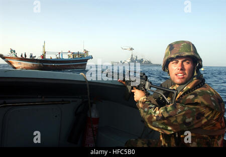 A bordo di una imbarcazione di pattuglia, un Italiano Marine, con una Beretta 5,56 mm SC70/90 fucile da assalto, dall'Italiano classe Maestrale fregata, la sua scirocco (F 573), in background consente di impostare la sicurezza per il suo team di sicurezza a bordo di un cargo locale dhow per condurre una ricerca della nave. SCIROCCO, lungo con un AB212ASW elicottero, rimane vicino per fornire funzioni di protezione aggiuntive e linee guida per il team di imbarco. La multinazionale combinati Task Force 150 (CTF-150) istituita per monitorare, ispezione a bordo, e arrestare il sospetto che la spedizione di proseguire la guerra al terrorismo e include operazioni che hanno luogo attualmente in Foto Stock