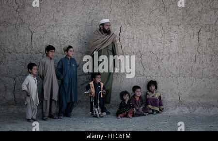 Gli abitanti di un villaggio di guardare come un pattugliamento comune di polacco esercito di soldati e poliziotti afghani di passaggio. Pattugliamento comune in provincia di Ghazni 274024 Foto Stock