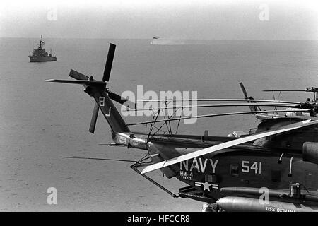 L'oceano dragamine USS infliggono (MSO-456) e un RH-53D Sea Stallion elicottero condurre operazioni minesweeping vicino all'assalto anfibio nave USS OKINAWA (LPH-3). Un elicottero contromisure Mine Squadron 14 (HM-14) RH-53D è parcheggiata sul ponte di volo dell'Okinawa in primo piano. Il rilevamento delle mine in Elicottero e nave di superficie, Golfo Persico, 1987 Foto Stock