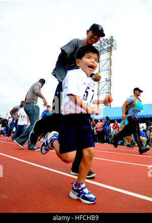 Naval Mobile Battaglione di costruzione 3's Builder Constructionman Alex Abeyta motiva il suo atleta durante la 40 yard dash durante la Kadena Special Olympics. Volontari da Naval Mobile Battaglione di costruzione 3 sia aiutato a prepararsi per il xiv annuale di Kadena Special Olympics e applauditi atleti il giorno dell'evento. La Kso è stata istituita dal XVIII Wing Commander nel 1999 come una via per costruire relazioni con le comunità vicine e i rappresentanti locali del governo fornendo allo stesso tempo una significativa attività per le particolari esigenze di bambini e adulti. L'evento è cresciuto da circa 1 Foto Stock