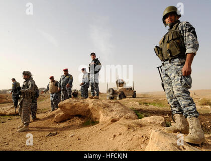 Un iracheno Polizia Federale officer, parte di un iracheno del comandante di sicurezza personali di distacco, mantiene la guardia, mentre U.S. Soldati, assegnati al 3° Battaglione, 8 reggimento di cavalleria, 3° Brigata pesante Team di combattimento, 1° Divisione di cavalleria e soldati con la terza della polizia federale il team di transizione, funzionano in combinazione con la Iraqi poliziotti federali durante un cordone e missione di ricerca presso un agriturismo nei dintorni di Mosul, Iraq, nov. 5, 2009. La zona era sospettato di essere utilizzato come un veicolo carico di esplosivo di fabbrica del dispositivo. Operazione Iraqi Freedom 220994 Foto Stock