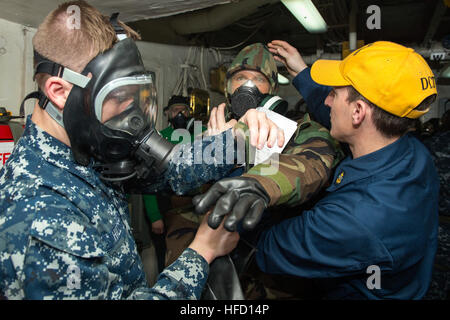 Mar Rosso (19 marzo 2013) Aviation Electronics tecnico di terza classe Jonathan S. Hill e Chief Aviation Electronics Technician Byron D. Tim help Aviation Electronics tecnico di terza classe Matteo A. Beanblossom mettere il suo equipaggiamento protettivo personale e MC2P maschera a gas durante una sostanza chimica, biologica e radiologica quartieri generali trapano a bordo della portaerei USS Dwight D. Eisenhower CVN (69). Dwight D. Eisenhower è distribuito negli Stati Uniti Quinta Flotta area di responsabilità promuovere le operazioni di sicurezza marittima, teatro la cooperazione in materia di sicurezza gli sforzi e le missioni di sostegno come parte dell'OPERAZIONE E Foto Stock