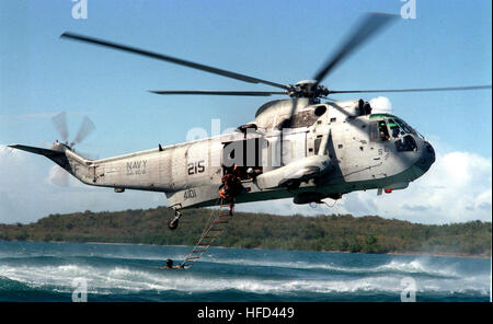 970317-N-8977R-006 A U.S. Navy SH-3H Sea King elicottero si libra sopra l'acqua a recuperare l'eliminazione degli ordigni esplosivi tecnici salendo una scala per l'aereo il 17 marzo 1997. I membri del team di l'eliminazione degli ordigni esplosivi Mobil unità 2 e gli equipaggi in elicottero dalla flotta squadrone composito 8 sono la pratica di inserimento e operazioni di recupero al largo della costa della stazione navale Roosevelt strade, Puerto Rico. DoD foto di Sottufficiali di prima classe Michael Rinaldi, U.S. Navy. SH-3H re del mare Foto Stock