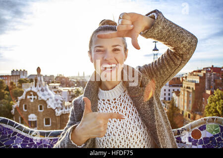 Firma di Barcellona style. Sorridendo viaggiatore eleganti donna a ricoprire in Barcellona, Spagna inquadratura con le mani Foto Stock