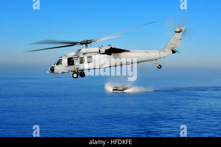 Un elicottero MH-60S Knighthawk vola sopra un cuscino aereo di un mezzo da sbarco dal molo di trasporto anfibio USS New Orleans (LPD 18) durante un esercizio di certificazione con il Boxer Expeditionary Strike Group, preparandosi per il futuro dispiegamento nell'Oceano Pacifico. Foto Stock