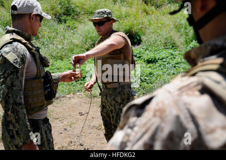 L'eliminazione degli ordigni esplosivi di prima classe Giuseppe Tumminello (centro) di Oak Ridge, Tennessee, e Chief l'eliminazione degli ordigni esplosivi Michael Solis (sinistra) di Camden, N.J., entrambi membri della superficie navale Warfare Center, Indian Head l'eliminazione degli ordigni esplosivi divisione tecnologica dimostrare per forza di 4 società di ricognizione Marines come rimuovere un tappo di sabbiatura da un contenitore isolato durante la demolizione di formazione presso la Baia di Kaneohe gamma Training Facility 20 Agosto, 2014. Tumminello e Solis, sia l'eliminazione degli ordigni esplosivi e gli esperti di demolizione, hanno contribuito ad aumentare la quarta forza di ricognizione della società Foto Stock