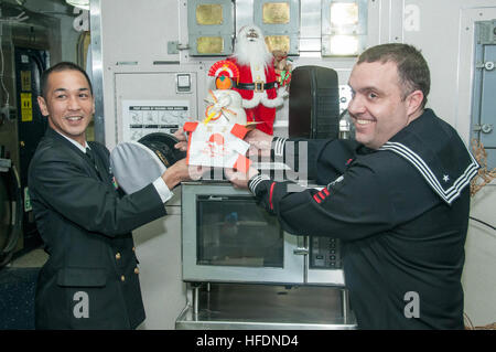 151218-N-RU971-438 Sasebo, Giappone (dec. n. 18, 2015) - Japan Maritime Self Defence Force (JMSDF) Capo Hirosahi Nishitani, da Shirane-class destroyer JDS Kurama (DDH 144), presenta una tradizionale torta di riso alla comunicazione di massa Specialist 1a classe Ty Connors, Bonhomme Richard's public affairs officer (arruolato), il pasticcio deck a bordo distribuita Amphibious Assault nave USS Bonhomme Richard (LHD 6). Bonhomme Richard è la nave di piombo del Bonhomme Richard anfibio gruppo pronto e viene distribuita a Sasebo, Giappone negli Stati Uniti 7 flotta area di operazioni. (U.S. Foto di Marina di Massa Foto Stock