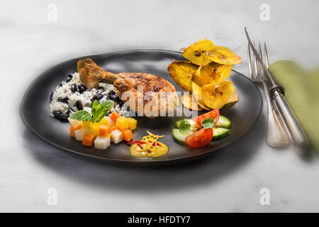 Tipico cibo cubano, pollo, riso con i fagioli neri, fritti banana chips, insalata e verdure. CUBA. kuba stile alimentare Cibo per lo styling Foto Stock