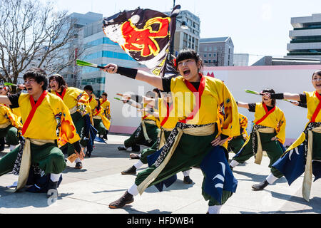 Giapponese Yosakoi Dance Festival. Donne giovani danzatori in giallo yukata giacche, azienda ventilatori verde, formazione balli in piazza della città. Foto Stock