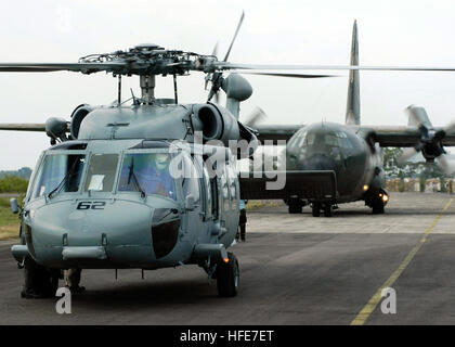 050103-N-4166B-210 Aceh e Sumatra, Indonesia (GEN. 3, 2005) Ð un MH-60S Knighthawk elicottero, assegnato all'ÒGunbearersÓ di elicottero di lottare contro lo squadrone di supporto undici (HC-11), il distacco di due e un australiano C-130 Hercules aeromobili cargo pronti per il decollo al Sultan Iskandar Muda Air Force Base in Aceh e Sumatra, Indonesia. Elicotteri assegnati al vettore Air Wing due (CVW-2) e marinai da Abramo Lincoln stanno conducendo le operazioni umanitarie in scia dello tsunami che ha colpito il Sud Est Asiatico. La Abraham Lincoln Carrier Strike gruppo è attualmente operativo in Oceano Indiano di Foto Stock