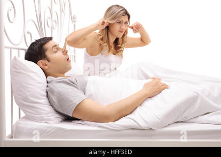 Uomo dorme e il russamento accanto a una donna collegando le sue orecchie isolati su sfondo bianco Foto Stock