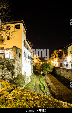 Scena urbana di un fiume che attraversa la parte vecchia della città di Granada, Spagna, scattata di notte Foto Stock