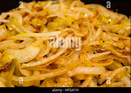 Golden brown, saltato le cipolle in una padella in ghisa. Foto Stock