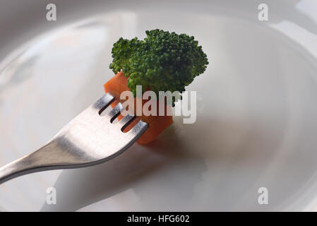 Pezzo di broccoli sulla forcella sulla piastra bianca Foto Stock