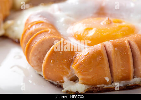 Close up di frittura di salsicce e uova su piastra bianca Foto Stock