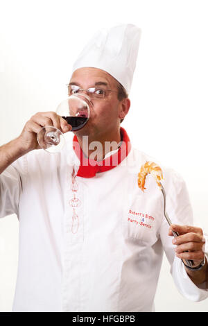 Lo Chef degustazione vino rosso, tenendo un re boreale sulla forcella Foto Stock