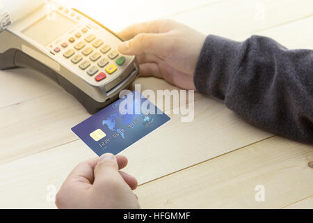 Mano del cassiere in possesso di una carta di credito e EDC macchina o terminale carte di credito. Carta di credito concetto e il terminale sul legno. Foto Stock