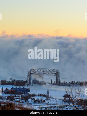 Il lago passa sotto l'antenna di Duluth ponte di sollevamento contro uno sfondo di fumo di mare oltre il Lago Superiore Foto Stock