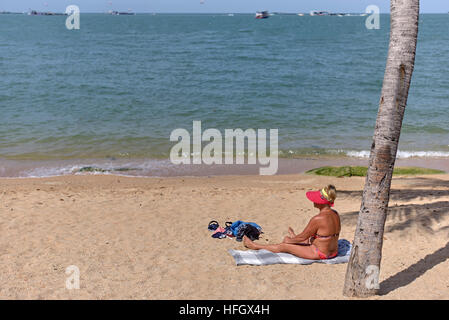 Donna sola spiaggia. Bikini rivestito femmina di sole su una spiaggia tropicale. Pattaya Thailandia S. E. Asia Foto Stock