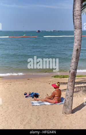 Donna sola spiaggia. Bikini rivestito femmina di sole su una spiaggia tropicale. Pattaya Thailandia S. E. Asia Foto Stock