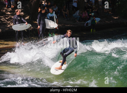 Surfer fa un giro su onde artificiali in Eisbach in Monaco di Baviera Englisher Garten, Germania. Foto Stock