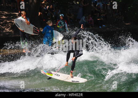 Surfer fa un salto sul artificiale onda permanente nel Eisbach in Monaco di Baviera Englisher Garten, Germania. Foto Stock