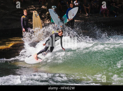 Surfer fa un sul artificiale onda permanente nel Eisbach in Monaco di Baviera Englisher Garten, Germania.